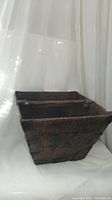 Full view of the antique wooden basket showing its trapezoidal shape, dark wood finish, and metal bracket reinforcements at corners.