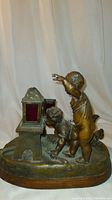 Front view of bronze lamp showing two children figurines playing by a lantern on oval base.