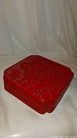 Side view of the red lacquer jewelry box showing intricate carved floral design and layered construction.