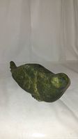 View of the walrus soapstone carving lying on its side, showing the smooth polished surface and natural vein patterns in the green stone.