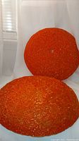 Two orange colored spun Lucite ceiling light shades, dome shaped, stacked closely together showing texture and color under diffuse lighting.