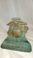 Front view of the bronze doorstop showing the USMC emblem with eagle, globe, and anchor detailing and green patina.
