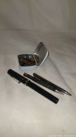 Photo showing vintage Schaeffer fountain pen, pencil, and metal tin with extra nibs on light background.