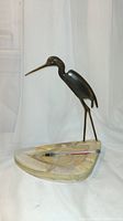 Natural stone ashtray with a standing metal bird sculpture, side view showing the ashtray base and bird's legs