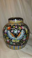 Front view of the jar showing colorful butterfly and gourd motifs on black background.