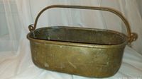 Side angle showing the pot's length, rectangular shape, and cast iron handle mounted on rings at each end.