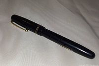 Side view of black vintage Swan Mabie Todd fountain pen with gold clip and two gold bands on the cap.