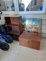 Full view of shelving unit, wooden box, and plaster painting with village scene