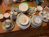 Overall view of assorted dishes, plates, bowls and coffee cups arranged on wooden table