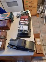 Three model cars on a table including the 1958 Edsel Citation model on a black base and two other antique style model cars with black bodies.
