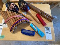 Overview of multiple instruments on a wooden table including maracas, pan flute, wooden flute, and harmonicas.