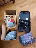 Box containing a vanity mirror with attached light, electric hair clippers in a black case, and some grooming accessories including shoe brushes.