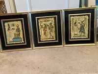Three framed Egyptian prints with black mats and gold trim, displayed on carpet