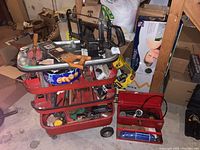 Metal tool cart filled with assorted tools and hardware, showing overall lot content.