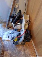 View of the lot showing various items including cords, portable saw, and mosquito light next to wood cabinet and floor.