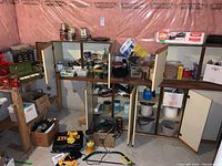 Overview of wall with lower shelves, cabinets removed and floor showing toolboxes and organizers