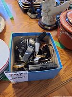 Top view of a blue box filled with multiple men's watches showing various metal bands and watch faces.