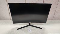 Front view of the 27-inch curved Samsung monitor showing the screen and stand on a white surface.