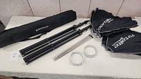 Full contents of the set displayed including two folded softboxes, two tripods, metal rods, and brackets on a white surface.