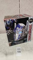 Front view of the boxed Transformers Optimus Prime voice changer helmet, showing product image and branding with Premier Edition label.