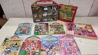 Wide view of all items in the lot including the farm animal figurines in cubby-style packaging, multiple floor puzzles, the magnetic dolls box, and several sticker sheets.
