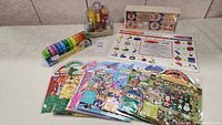 Overview of all items in lot including condiment set, wooden caterpillar, learning mat, puzzles, and stickers