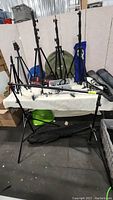 Overview of tripods and stands on table and floor, including Manfrotto boom stand and additional light stands