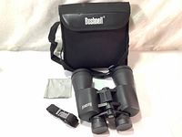 Front view of Bushnell binoculars with carrying case and strap laid out