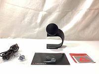 Photo of Thronmax Fireball microphone on metal stand, USB cable, connection guide, and branded stickers laid out on white surface.