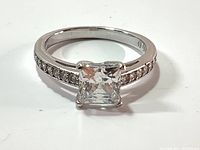 Front view of the silver-tone ring with large square princess cut Swarovski crystal center stone and pave crystals on the band.