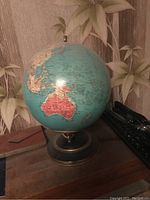 Unlit view of 10 inch glass globe with detailed map and countries, mounted on brass-colored stand.