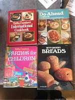 Photo showing four cookbooks out of six: International, Do-Ahead, Parties for Children, and Breads, arranged in a 2x2 format.