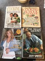 Photo showing four cookbook covers: Cooking with Regis & Kathie Lee, Lucy Waverland Cooking School Cookbook, Home Cooking with Trisha Yearwood, and The Frugal Gourmet by Jeff Smith.
