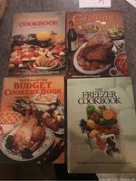 Four large cookbooks arranged on floor, titles visible