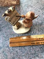 Front view showing the child conductor figurine facing two birds on sheet music on a music stand with a ruler for scale indicating approx. 4 inches tall.
