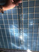 Full view of the silver-tone chain necklace hung vertically showing length and chain design against blue tile background.