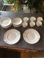 Full set of vintage china laid out on counter showing plates, saucers, and teacups.