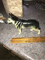 Side profile view of the German Shepherd porcelain figurine on a kitchen countertop, ruler included for scale showing approximately 7 inches length.