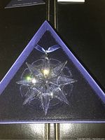Close-up of Swarovski 2009 crystal star Christmas ornament in blue triangular box with soft velvet lining.