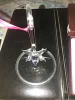 Crystal star ornament suspended on clear acrylic ring-and-post stand placed on black surface