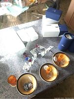 Full view of lot showing three orange plastic bottles containing crystal chips, broken crystal pieces, and multiple Swarovski boxes including blue branded boxes and white boxes.