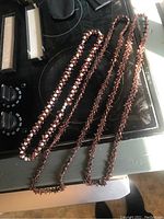 Photo of three necklaces laid on a stove showing two brown beaded strands and one white and brown beaded necklace.