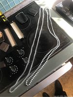 Photo of two long metallic beaded necklaces laid on a stovetop.