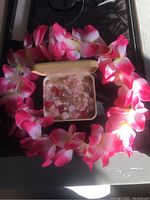 Photo showing pink and white fabric flower party lei surrounding a box containing a vintage pink and clear beaded necklace.