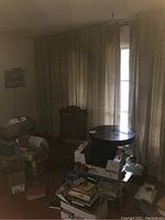 Curtains hanging closed covering windows, with boxes and furniture in the room surrounding them, showing overall curtain coverage and fabric color.