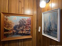 Two paintings against wooden wall, landscape on left and abstract on right
