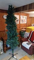 Full view of the 7-foot artificial Christmas tree with lights, standing in a room, showing the tripod metal base and branch density.