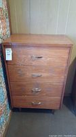 Front view of the vintage solid wood dresser showing four drawers each with a metal handle.
