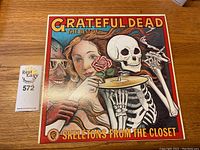 Front cover of Grateful Dead album Skeletons From The Closet featuring vibrant artwork of a skeleton with a woman and a rose.