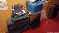 Photo showing stacked vintage luggage pieces with a Wardair Canada bag on top and blue translucent storage bin.